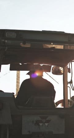 Silueta de un agricultor manejando una cosechadora al atardecer.
